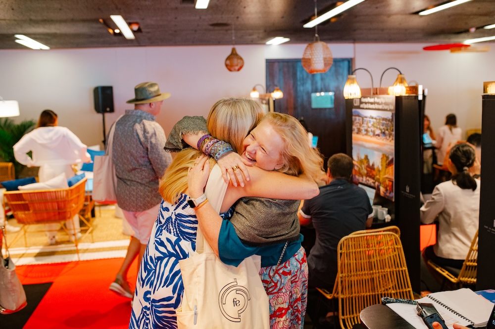 Delegates embracing in front of the Branded merchandise displayed at a DMC stand