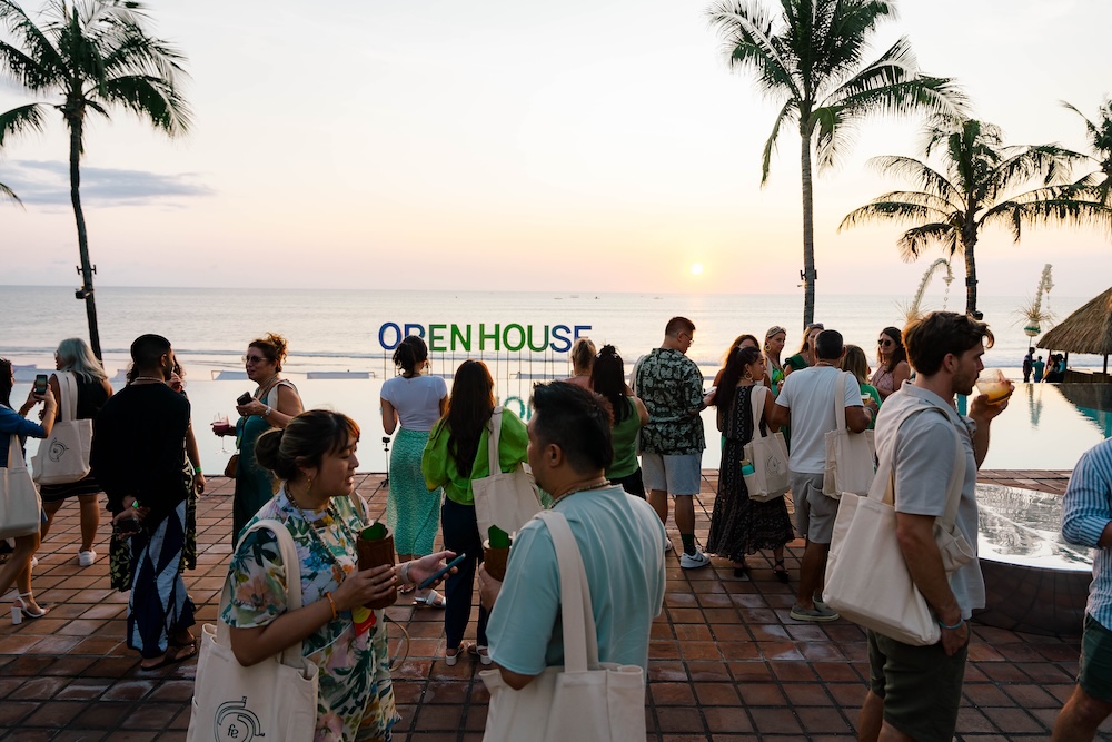Delegates networking under palm trees at open house