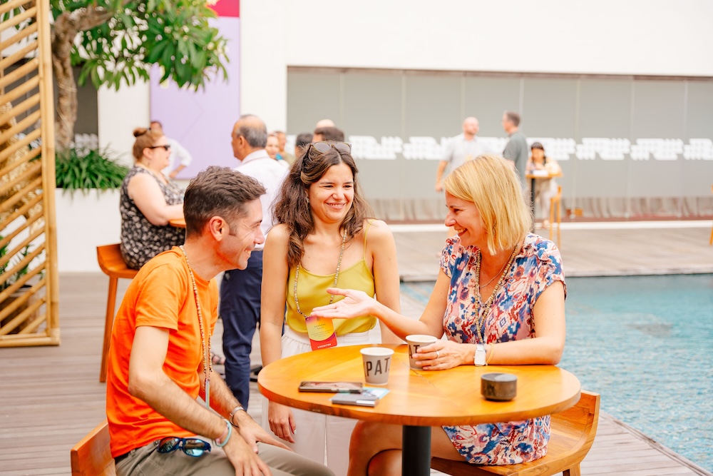 Delegates networking by the pool embracing barefoot business